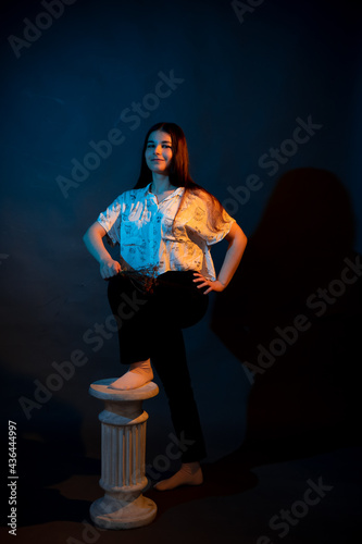 Girl on a stand on a dark background with multicolored light
