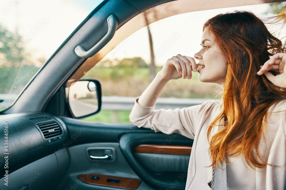 happy woman with red hair in front seat of car touching face with hands cropped view