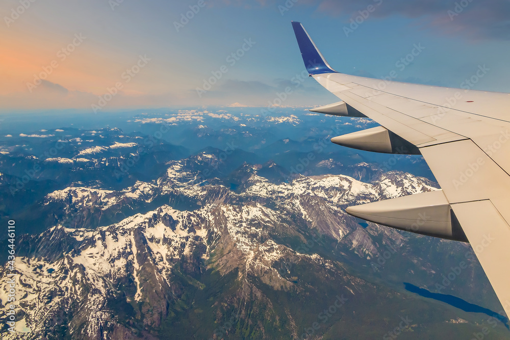 Fototapeta premium Flying over snow capped mountains, view of airplane wing, Seattle
