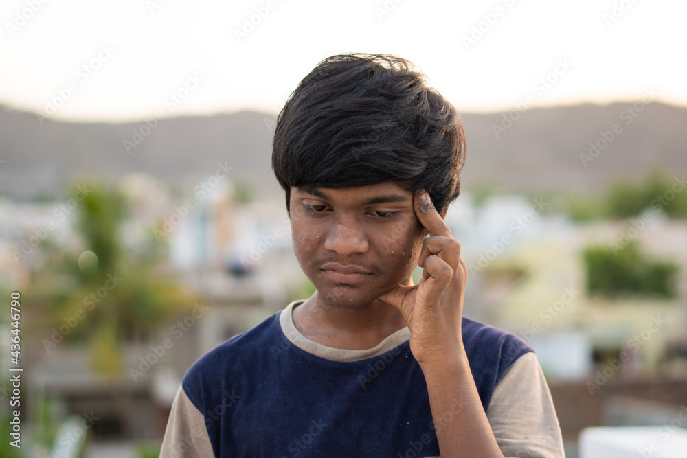 Portrait of a stressed Indian kid massaging his head due to the headache 