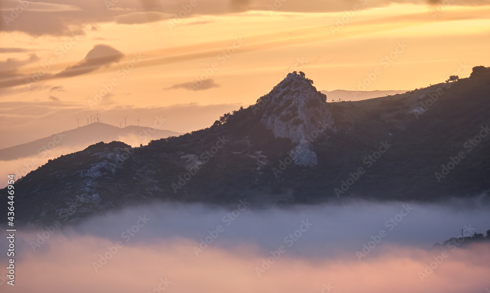 Siluetas de montañas al amanecer con una niebla en la parte baja de las montañas