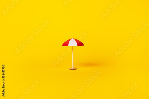 red and white beach umbrella over yellow background  summertime and vacation concept