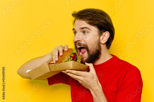 man in red t-shirt eating hamburgers fast food diet food yellow background