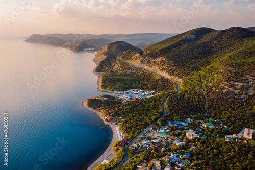 Photos Aerial view of coastline with blue sea, mountains with trees, cliffs with sunset light and clouds