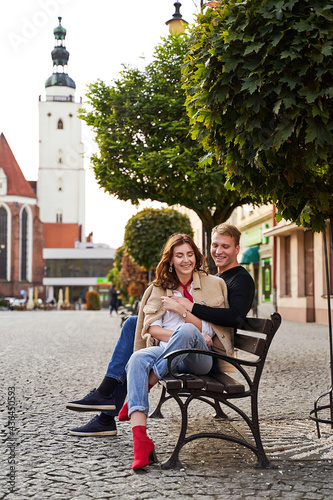 Obraz na plátně Beautiful young couple cuddling on a bench in a European town