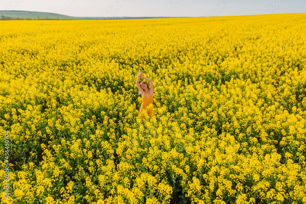 Obraz premium Aerial view of woman at blooming rapeseed field. Yellow flowers and happy young woman