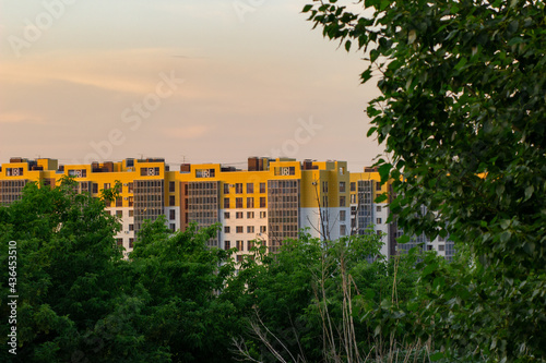 Volgograd / Russia - May 2021: bright new building, high-rise building framed by green foliage of trees