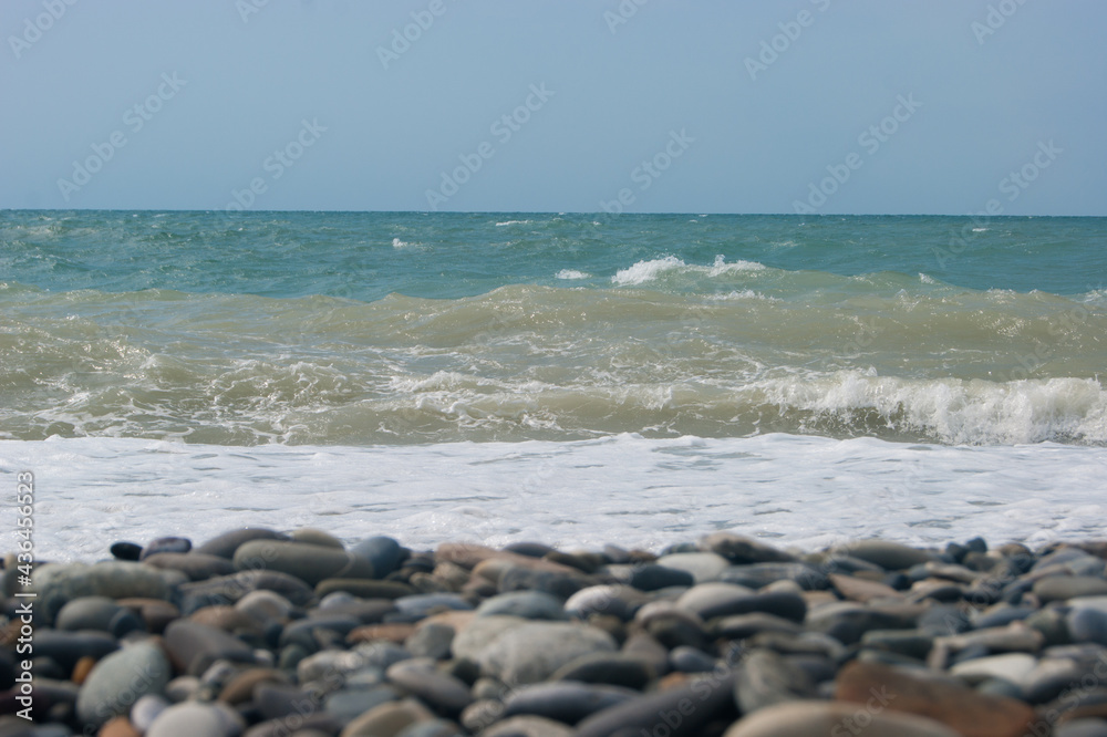 The Sea Wave of the Black Sea is a pebble beach. Smooth horizon, blue sky.