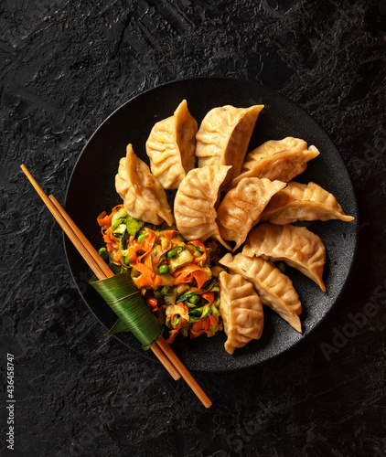 Asian Gyoza dumplings with pork meat and vegetables on a black background. Top view photo