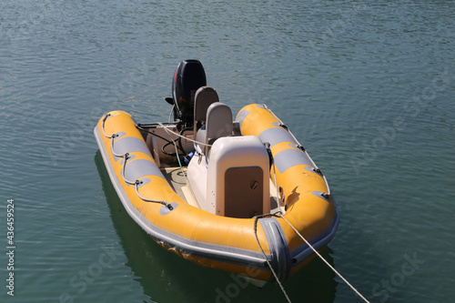 A bright yellow inflatable dinghy with outboard motor moored by the quayside in Fishguard, Pembrokeshire, Wales, UK. photo