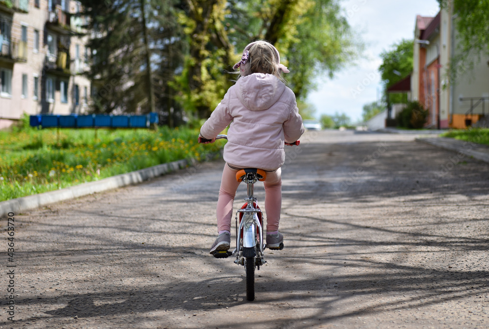Girl in pink clothes riding a bike on the road