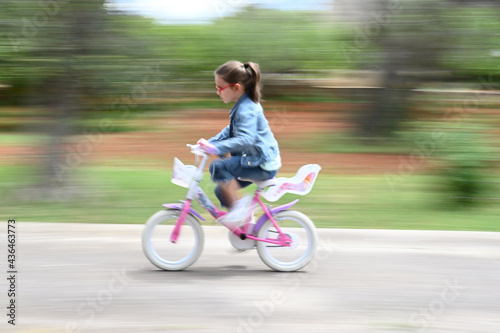 Ritratto di una bambina di sette anni alla guida della sua bicicletta.
