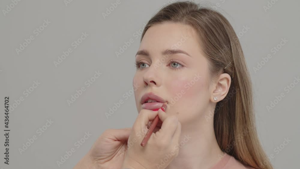 Makeup artist or stylist applies lipstick to the lips of the female model. Visagiste making make up applying lipstick on a lip. Professional makeup. Tutorial makeup master class. Making mua. Makeup artist or stylist applies lipstick to the lips of the female model. Visagiste making make up applying lipstick on a lip. Professional makeup. Tutorial makeup master class. Making mua.