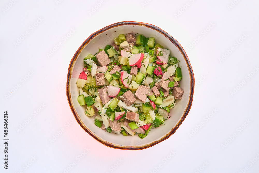 Okroshka salad of boiled eggs, meat and potatoes, fresh cucumber, radish and dill in a white round plate on a white background. Okroshka salad of boiled eggs, meat and potatoes, fresh cucumber, radish and dill in a white round plate on a white background.