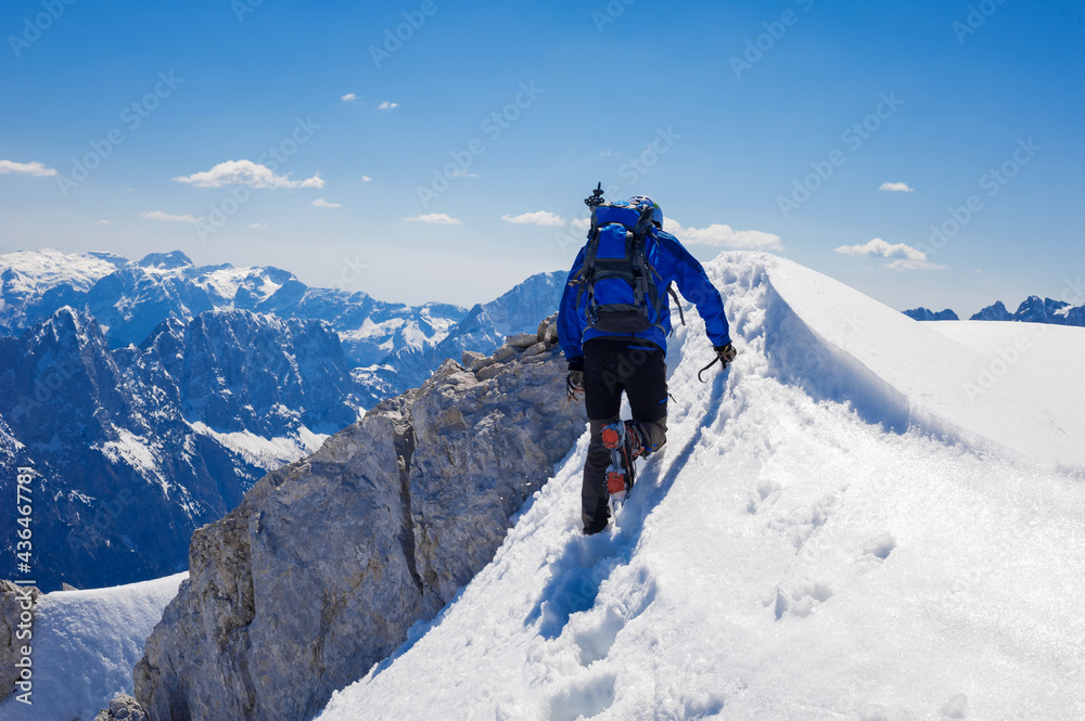 climber on the top of the alpine mountain Mala Mojstrovka against the backdrop of snowy alps