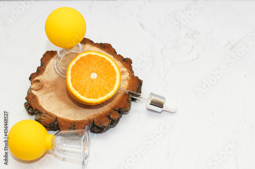 Vacuum massage anti-cellulite cups on a gray background with orange and oil. Self-massage for healthy skin. photo