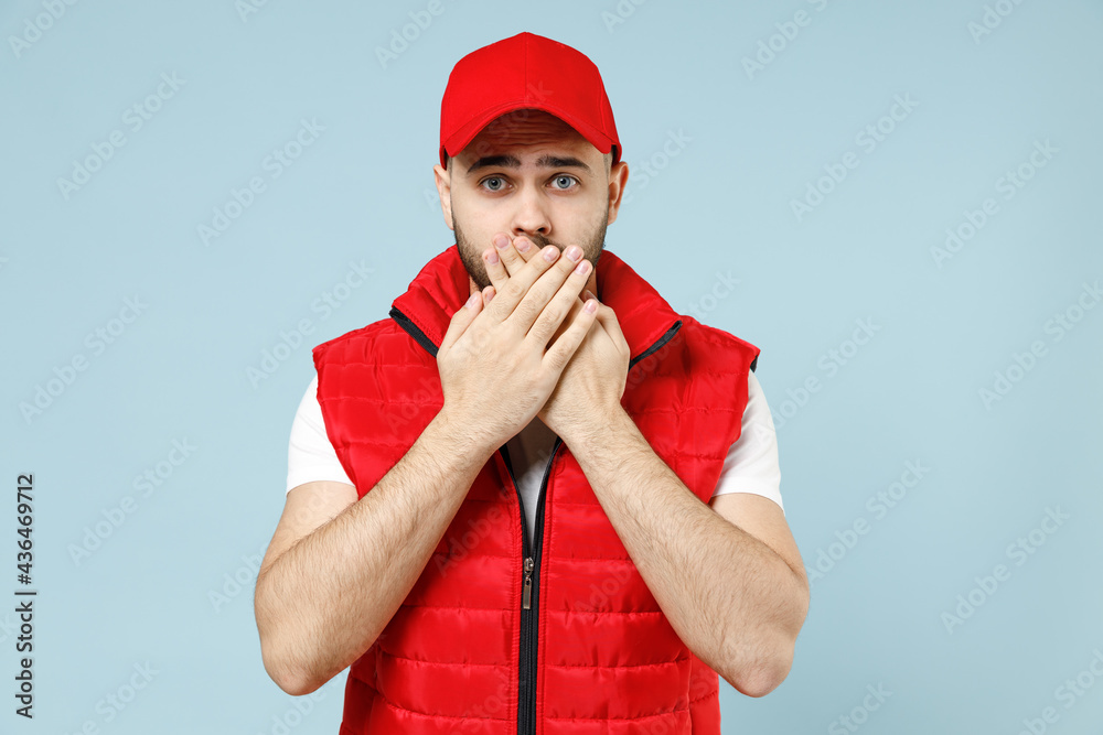 Professional sad tired worry delivery guy employee man in red cap white T-shirt vest uniform workwear work as dealer courier isolated on pastel blue color background studio portrait. Service concept. Professional sad tired worry delivery guy employee man in red cap white T-shirt vest uniform workwear work as dealer courier isolated on pastel blue color background studio portrait. Service concept.