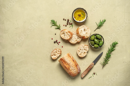 Fresh ciabatta bread with olive oil, olives and rosemary on a beige concrete background. Italian food. Top view, flat lay, copy space.