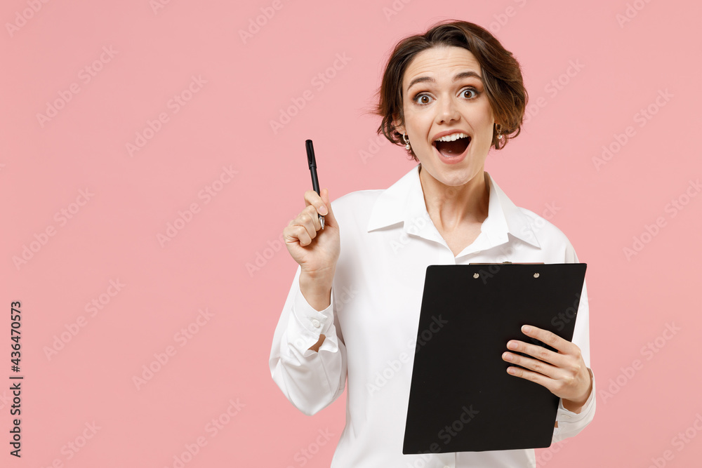 Young insighted employee business secretary woman corporate lawyer in classic formal white shirt work in office clipboard with papers write document hold finger up isolated on pastel pink background. Young insighted employee business secretary woman corporate lawyer in classic formal white shirt work in office clipboard with papers write document hold finger up isolated on pastel pink background.