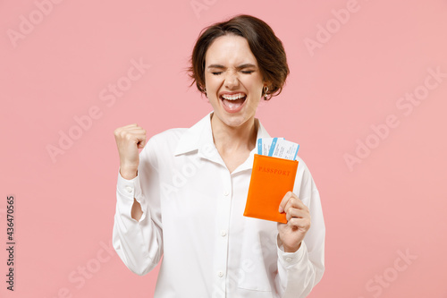 Traveler tourist employee business woman wear white shirt hold passport tickets do winner gesture isolated on pastel pink background Passenger travel abroad weekend getaway Air flight journey concept