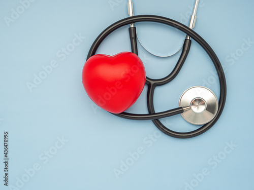 A stethoscope and red heart laid on a light blue background. Close-up photo. Top view. Flat lay. Space for text. Healthcare and medicine concept