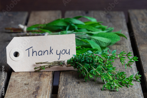 Fresh herbs and spices on wooden table thank you label