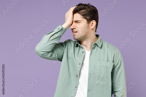 Young ashamed mistaken sad man 20s wearing casual mint shirt white t-shirt putting hand on face do facepalm epic fail gesture isolated on purple background studio portrait. People lifestyle concept