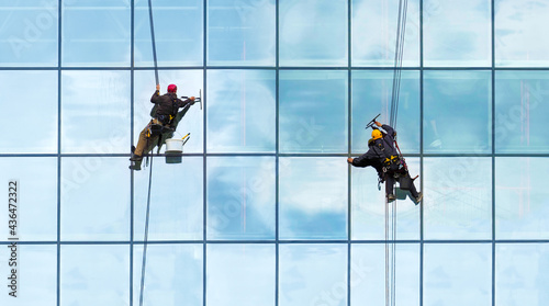Group of workers cleaning windows service on high rise building. Workers cleaning glass curtain wall. Special job concept, panoramic view