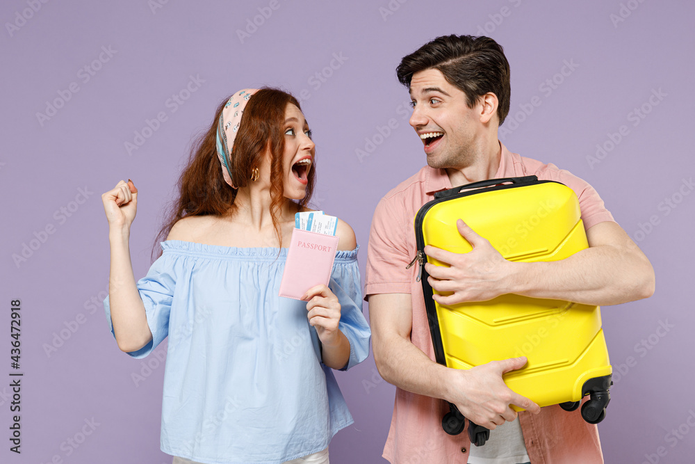 Two excited traveler tourist woman man couple in shirt hold suitcase passport tickets winner gesture isolated on purple background. Passenger travel abroad weekends getaway. Air flight journey concept Two excited traveler tourist woman man couple in shirt hold suitcase passport tickets winner gesture isolated on purple background. Passenger travel abroad weekends getaway. Air flight journey concept