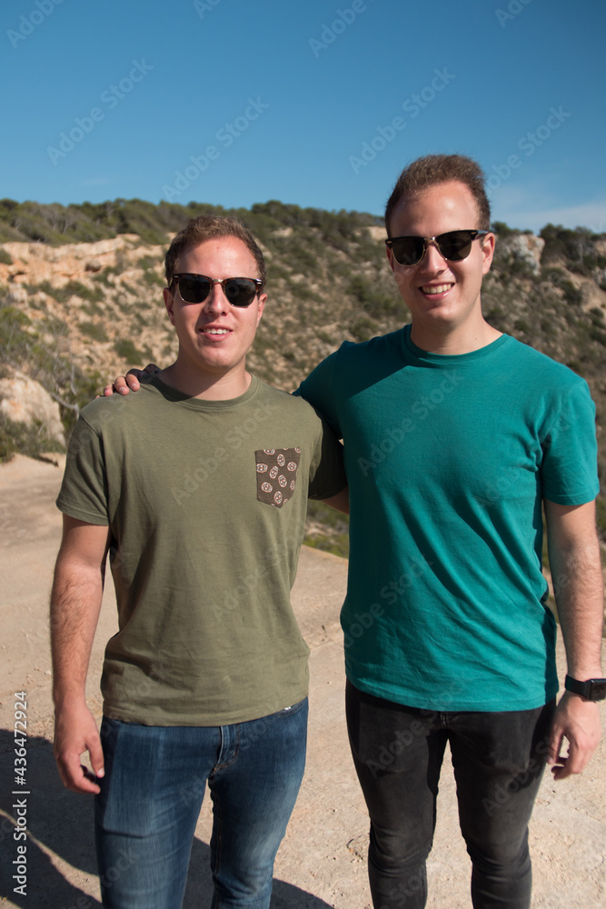 Twin brothers posing infront of a hill wearing sunglasses in a summer day. Twin brothers posing infront of a hill wearing sunglasses in a summer day.