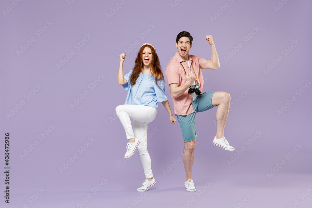 Full length traveler tourist woman man couple in summer clothes do winner gesture clench fist isolated on purple background. Passenger travel abroad on weekends getaway. Air flight journey concept