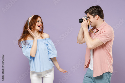 Two fun traveler tourist woman man couple in shirt taking photo portrait of girlfriend by camera isolated on purple background Passenger travel abroad on weekends getaway Air flight journey concept.
