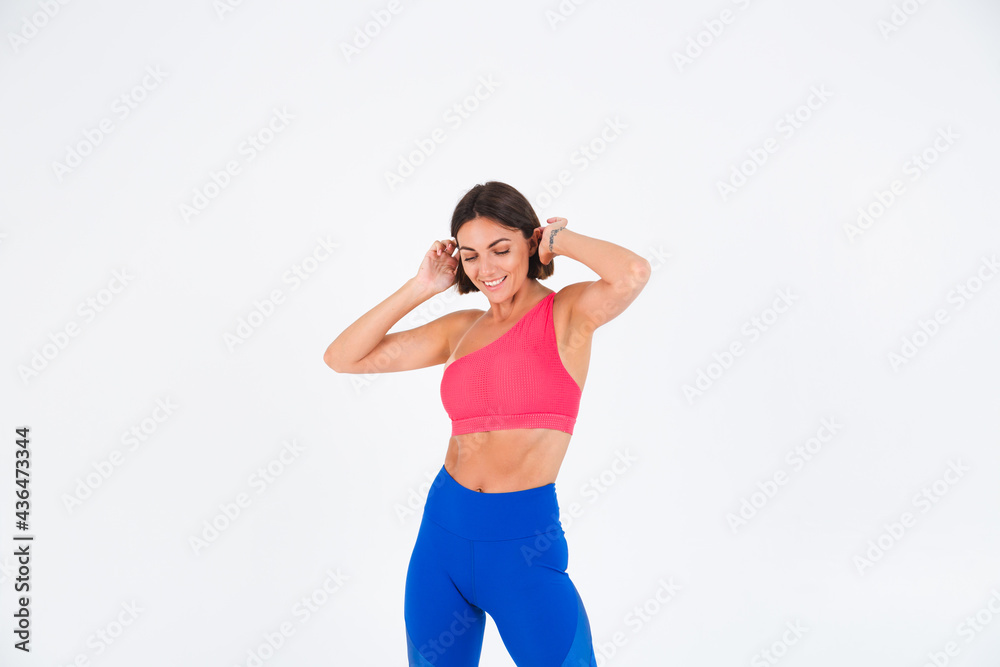 Fit tanned sporty woman with abs, fitness curves, wearing top and blue leggings on white background Fit tanned sporty woman with abs, fitness curves, wearing top and blue leggings on white background