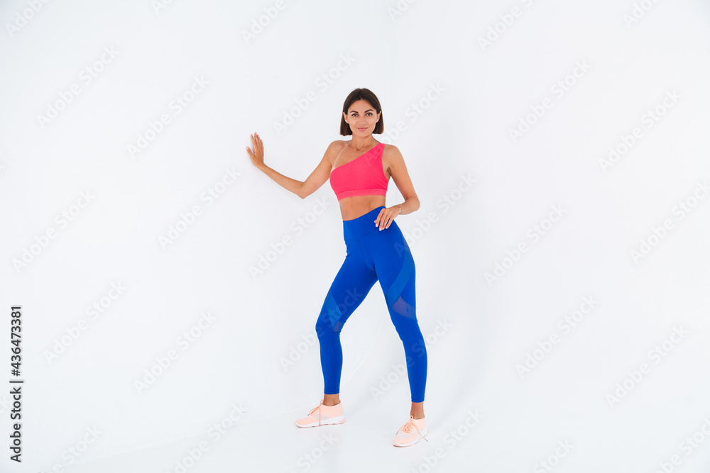 Fit tanned sporty woman with abs, fitness curves, wearing top and blue leggings on white background Fit tanned sporty woman with abs, fitness curves, wearing top and blue leggings on white background