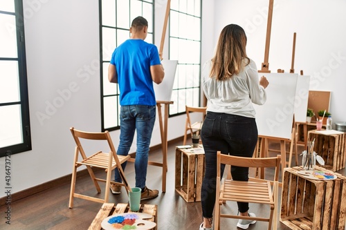 Two students on back view painting at art school.