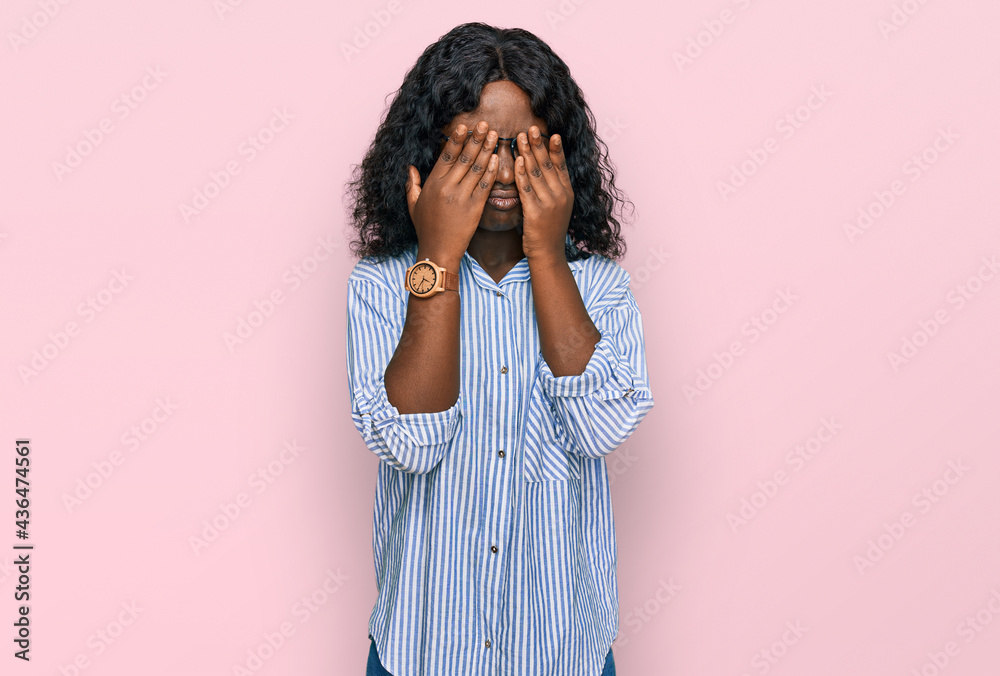 Beautiful african young woman wearing casual clothes and glasses rubbing eyes for fatigue and headache, sleepy and tired expression. vision problem Beautiful african young woman wearing casual clothes and glasses rubbing eyes for fatigue and headache, sleepy and tired expression. vision problem