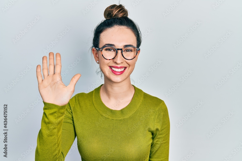 Young hispanic girl wearing casual clothes and glasses showing and pointing up with fingers number five while smiling confident and happy.