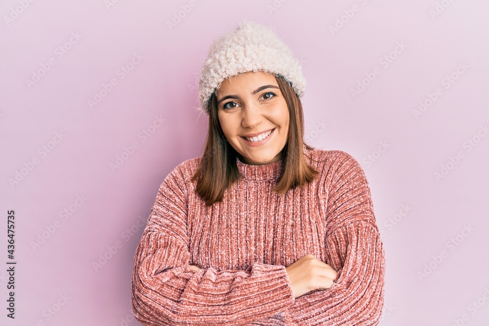 Young beautiful woman wearing wool sweater and winter hat happy face smiling with crossed arms looking at the camera. positive person. Young beautiful woman wearing wool sweater and winter hat happy face smiling with crossed arms looking at the camera. positive person.