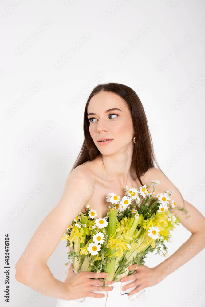 The girl is a brunette model, posing with a vegetable and flower bouquet in her hands. The girl is a brunette model, posing with a vegetable and flower bouquet in her hands.