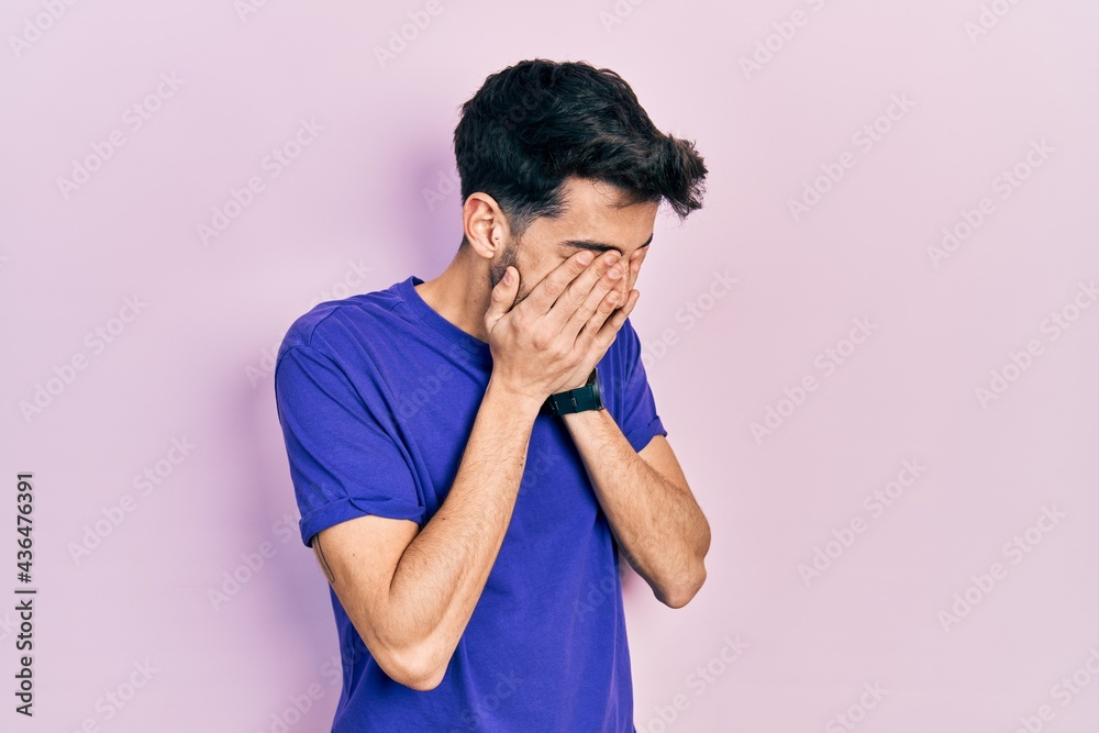 Young hispanic man wearing casual t shirt with sad expression covering face with hands while crying. depression concept. Young hispanic man wearing casual t shirt with sad expression covering face with hands while crying. depression concept.