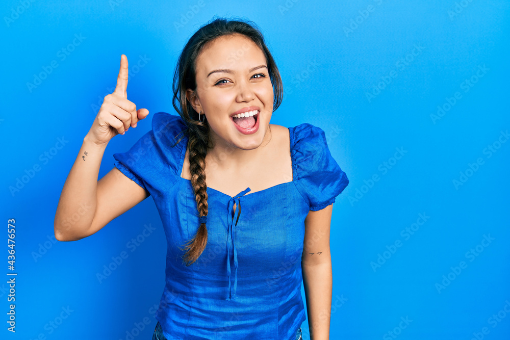 Young hispanic girl wearing casual clothes pointing finger up with successful idea. exited and happy. number one. Young hispanic girl wearing casual clothes pointing finger up with successful idea. exited and happy. number one.
