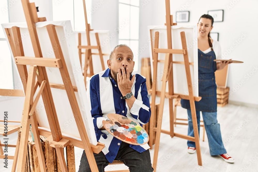 Senior artist man at art studio laughing and embarrassed giggle covering mouth with hands, gossip and scandal concept Senior artist man at art studio laughing and embarrassed giggle covering mouth with hands, gossip and scandal concept