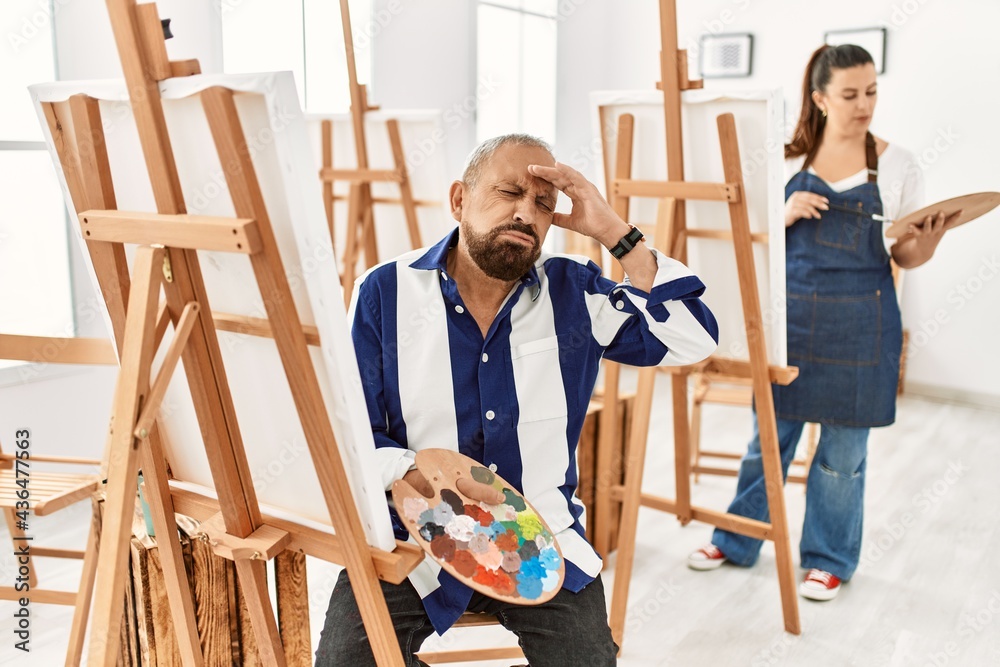 Senior artist man at art studio worried and stressed about a problem with hand on forehead, nervous and anxious for crisis Senior artist man at art studio worried and stressed about a problem with hand on forehead, nervous and anxious for crisis