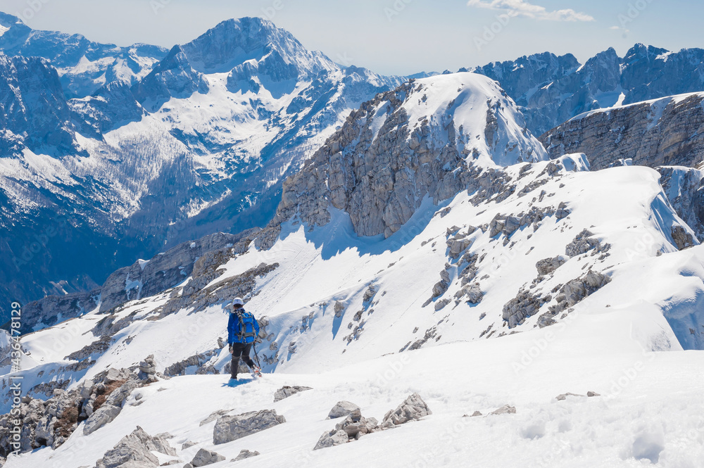 climber on the top of the alpine mountain Mala Mojstrovka against the backdrop of snowy alps 