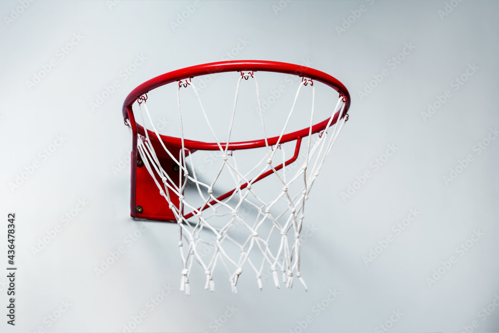 Close up view of red metal basketball hoop with sports net on white wall