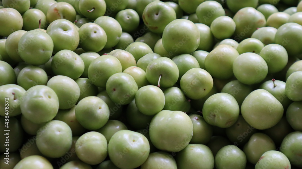 Close-up green plum fruits n the fruit market. Group of fresh green plums background on the market stand. Close-up green plum fruits n the fruit market. Group of fresh green plums background on the market stand.