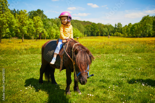 Canvas Print Adorable three years old girl riding a pony