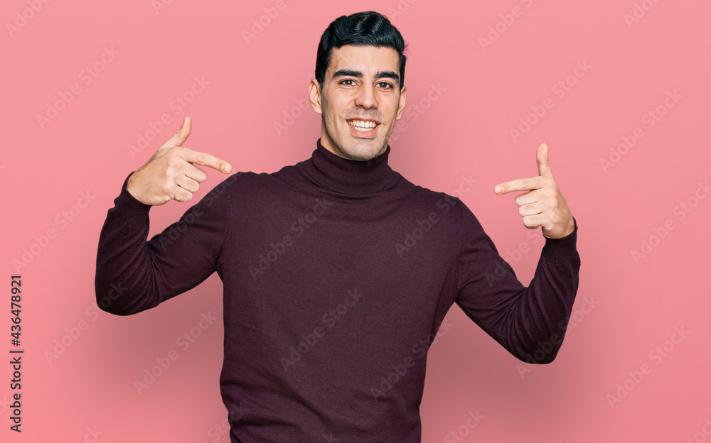 Fototapeta premium Handsome hispanic man wearing casual turtleneck sweater looking confident with smile on face, pointing oneself with fingers proud and happy.