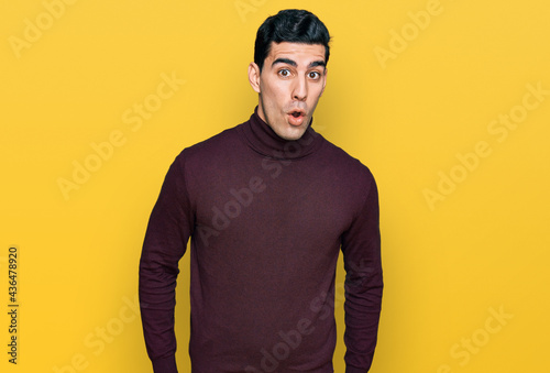 Handsome hispanic man wearing casual turtleneck sweater afraid and shocked with surprise expression, fear and excited face.
