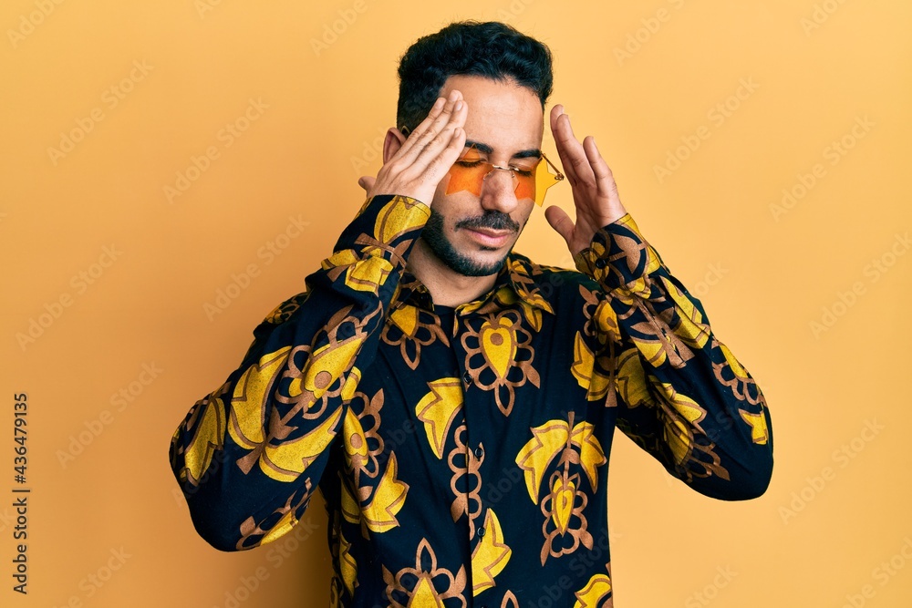 Young hispanic man wearing stylish sunglasses with hand on head, headache because stress. suffering migraine.